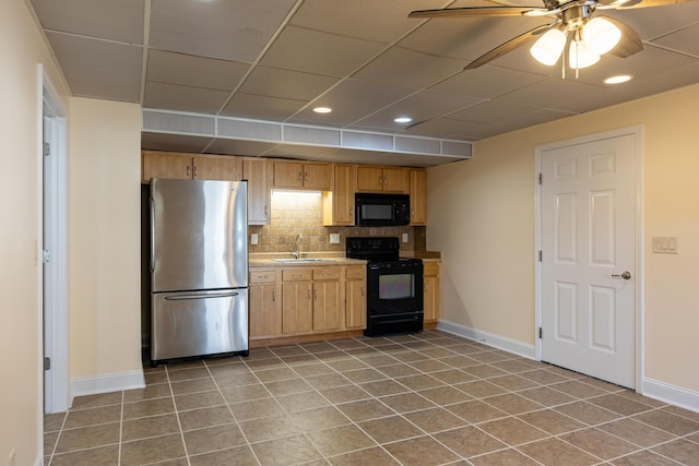 kitchen with a sink, baseboards, light countertops, backsplash, and black appliances