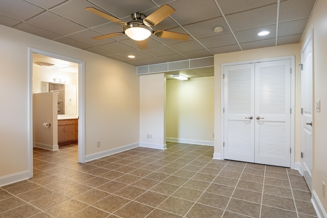 interior space featuring a paneled ceiling, ceiling fan, and baseboards