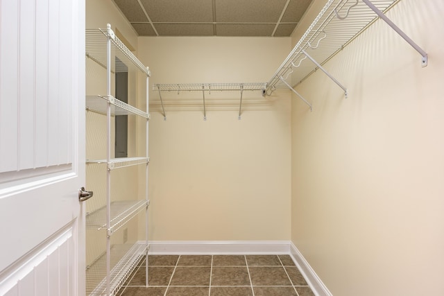 walk in closet featuring a drop ceiling and dark tile patterned floors