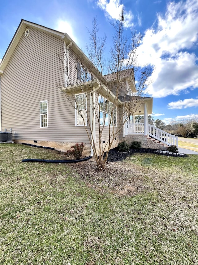 view of side of home featuring covered porch, crawl space, a lawn, and central air condition unit