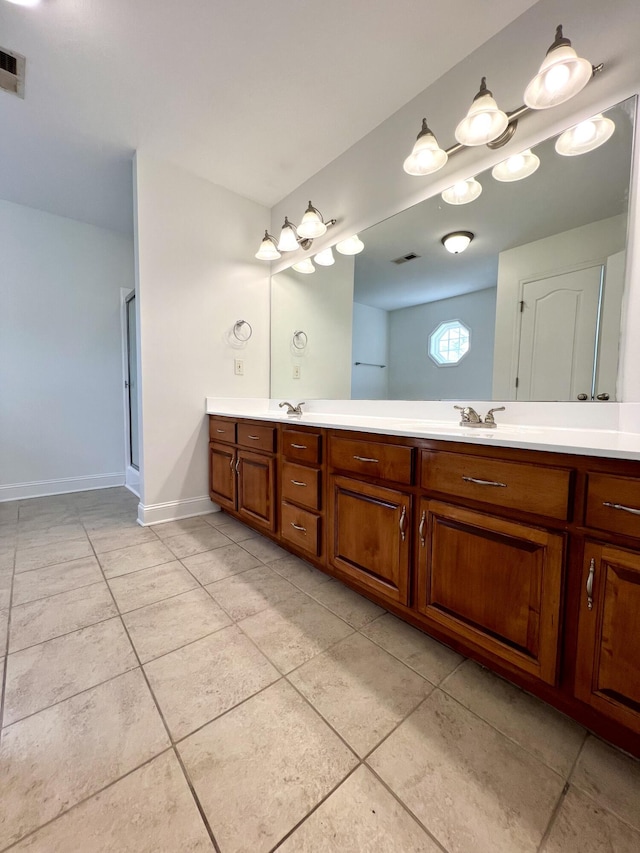 bathroom with double vanity, a sink, a shower stall, baseboards, and tile patterned floors