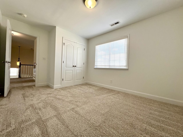 unfurnished bedroom with carpet floors, a closet, visible vents, and baseboards