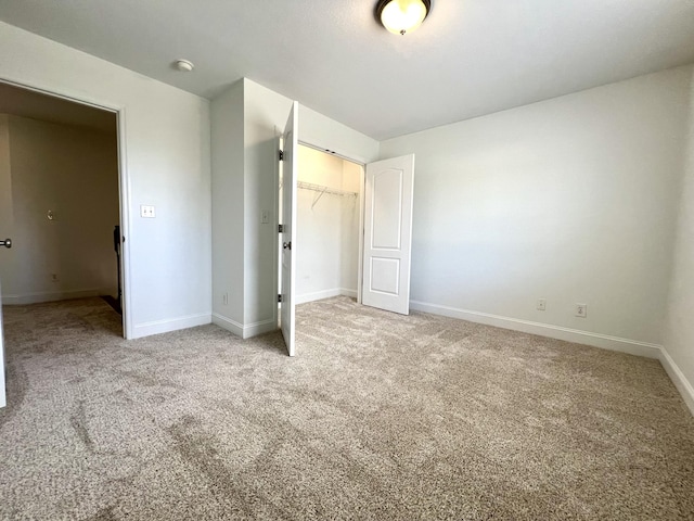 unfurnished bedroom featuring a closet, light colored carpet, and baseboards