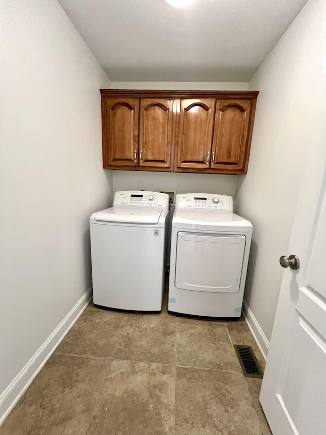 laundry area with washing machine and dryer, cabinet space, visible vents, and baseboards