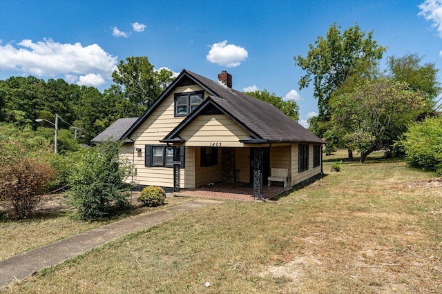 bungalow-style house featuring roof with shingles, a front lawn, and a chimney