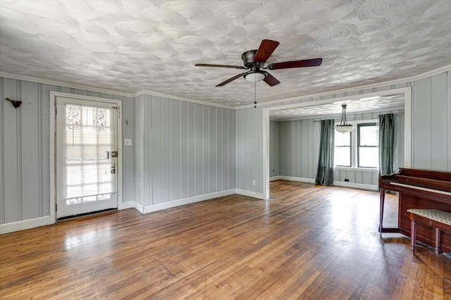 living room featuring crown molding, wood finished floors, baseboards, and a textured ceiling