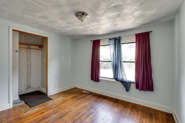 unfurnished bedroom with baseboards, visible vents, a closet, and wood finished floors