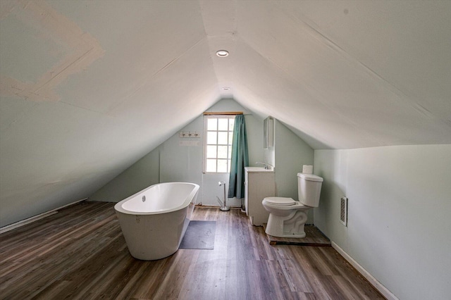 bathroom featuring lofted ceiling, a freestanding bath, toilet, and wood finished floors