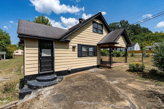 view of front of home featuring roof with shingles and a patio area