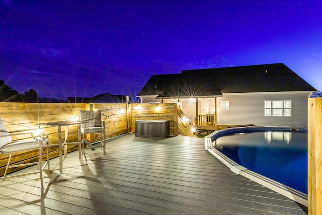 pool at night with an outdoor pool and a deck