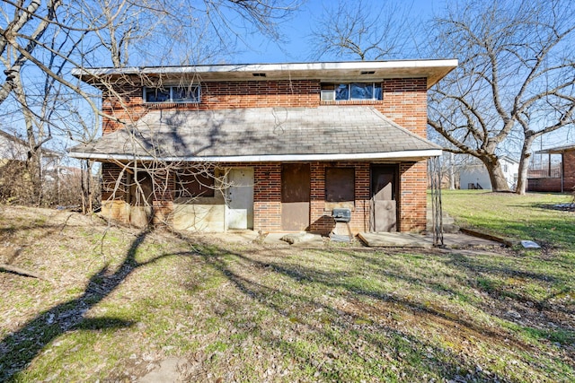 view of front facade featuring brick siding, a patio, and a front yard