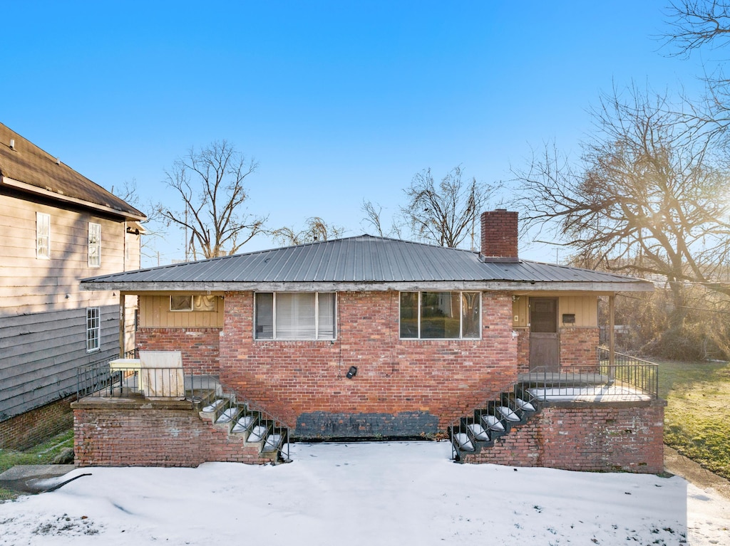 view of front of home with brick siding, metal roof, and a chimney