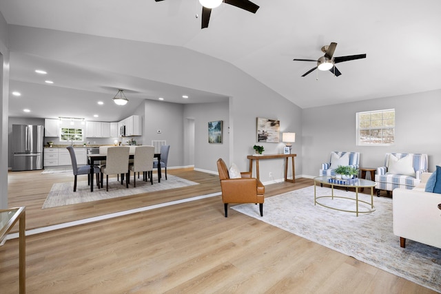 living room featuring lofted ceiling, light wood-type flooring, and baseboards