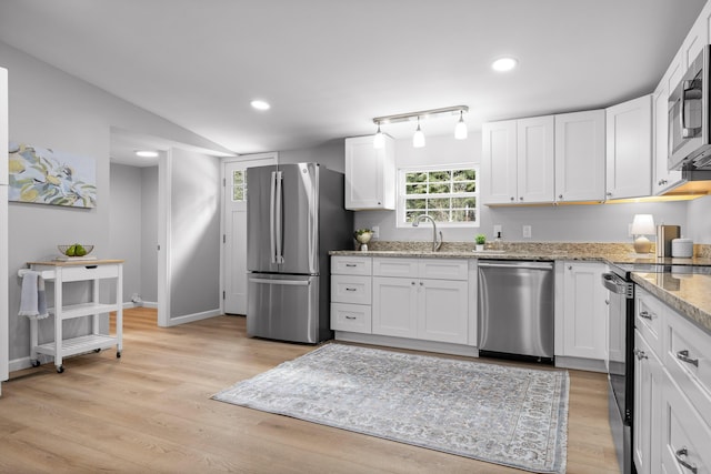 kitchen with white cabinetry, appliances with stainless steel finishes, light stone counters, and a sink