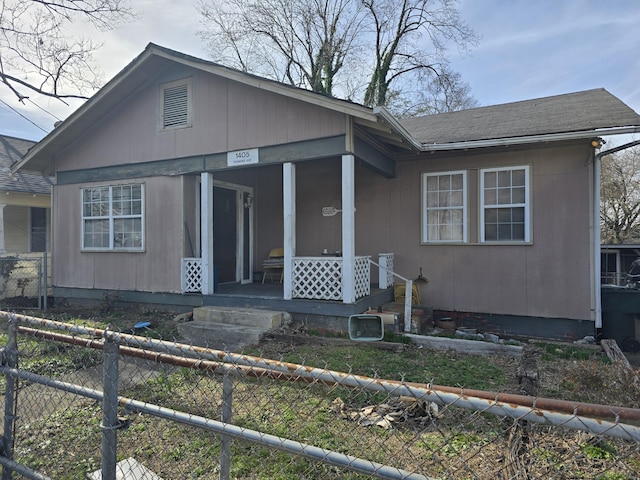 bungalow-style house with fence private yard, covered porch, and a shingled roof