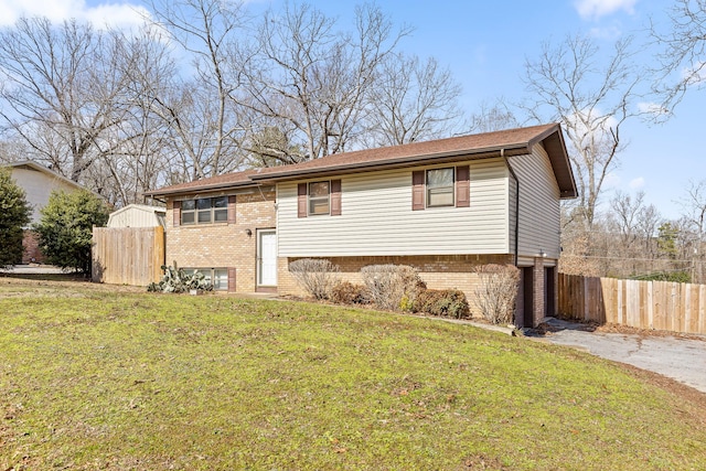 bi-level home with driveway, a front yard, fence, and brick siding