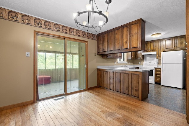 kitchen with white appliances, a peninsula, a chandelier, baseboards, and a textured ceiling