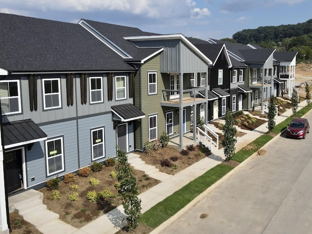 townhome / multi-family property featuring a shingled roof, a residential view, metal roof, a standing seam roof, and board and batten siding