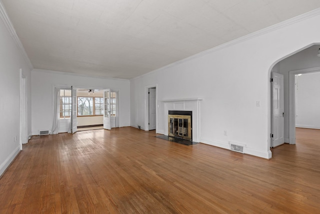 unfurnished living room with visible vents, arched walkways, wood finished floors, and a tile fireplace