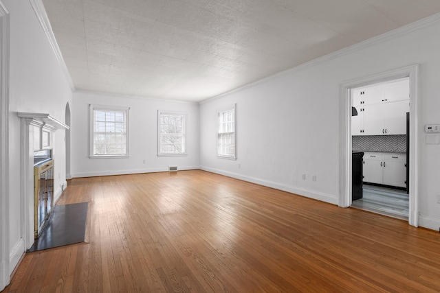 unfurnished living room featuring ornamental molding, baseboards, and wood-type flooring