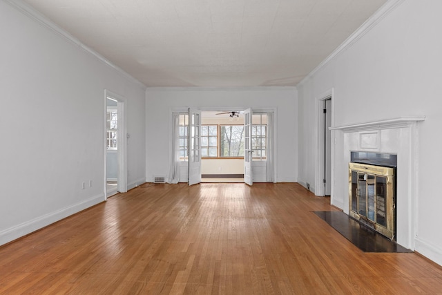 unfurnished living room featuring crown molding, baseboards, light wood finished floors, and a tile fireplace