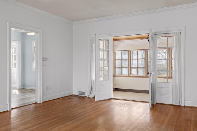 foyer with hardwood / wood-style floors, visible vents, baseboards, and ornamental molding