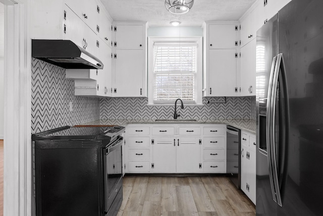 kitchen featuring a sink, light countertops, black range with electric stovetop, under cabinet range hood, and stainless steel fridge