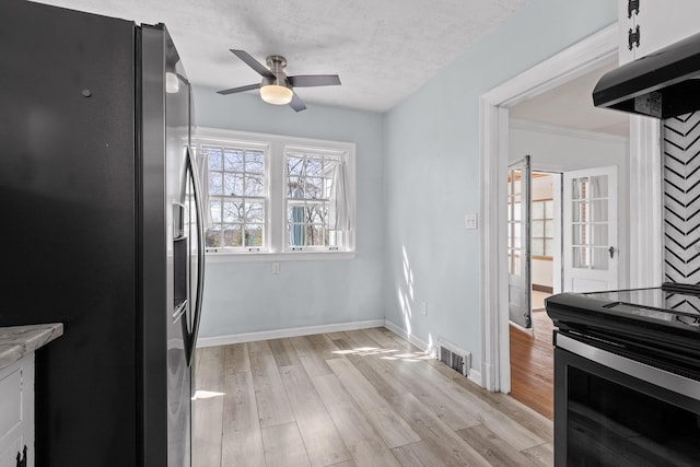 kitchen featuring under cabinet range hood, light wood-type flooring, stainless steel fridge, and baseboards