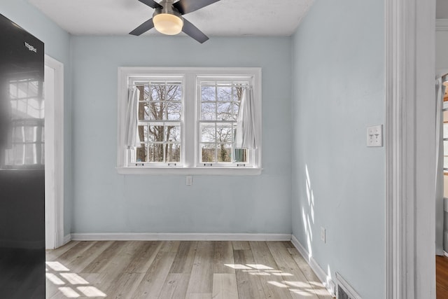 spare room featuring wood finished floors, baseboards, and ceiling fan