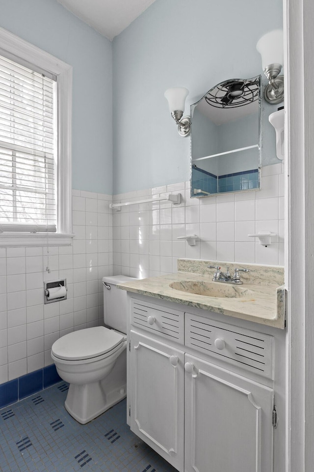 bathroom with vanity, tile patterned flooring, wainscoting, tile walls, and toilet