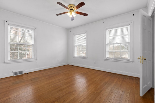 unfurnished room featuring visible vents, ornamental molding, hardwood / wood-style floors, baseboards, and ceiling fan