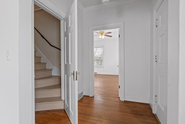 hallway featuring visible vents, wood finished floors, stairway, crown molding, and baseboards