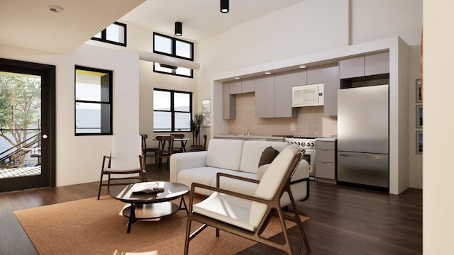 living room with a towering ceiling and dark wood-style flooring