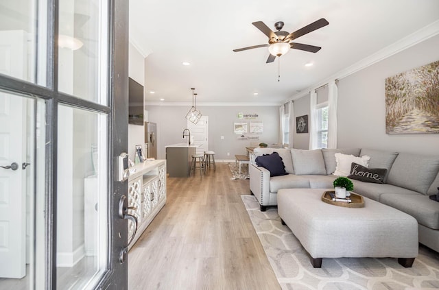 living room featuring recessed lighting, a ceiling fan, baseboards, ornamental molding, and light wood finished floors