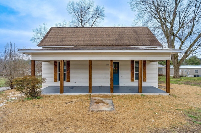 view of front of home featuring a patio area, a shingled roof, and a front yard