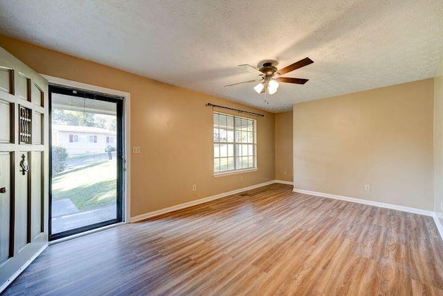 unfurnished room with light wood-style floors, ceiling fan, a textured ceiling, and baseboards