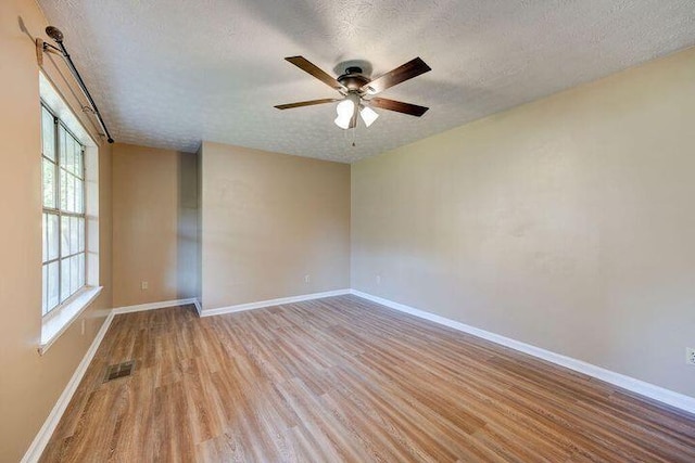 empty room featuring light wood-style flooring, visible vents, and baseboards