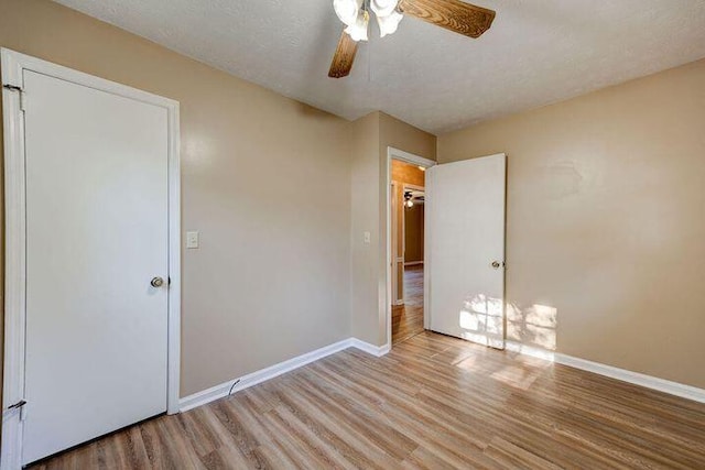 unfurnished bedroom featuring a ceiling fan, baseboards, a textured ceiling, and light wood finished floors