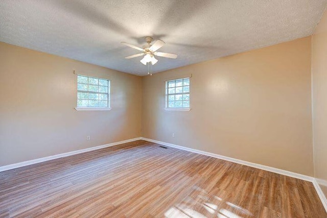 spare room featuring light wood finished floors, a wealth of natural light, and baseboards