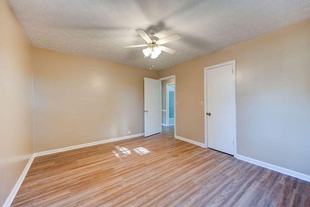 spare room with light wood-style flooring, baseboards, ceiling fan, and a textured ceiling