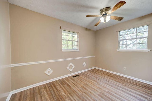 spare room with a ceiling fan, light wood-style flooring, baseboards, and a textured ceiling