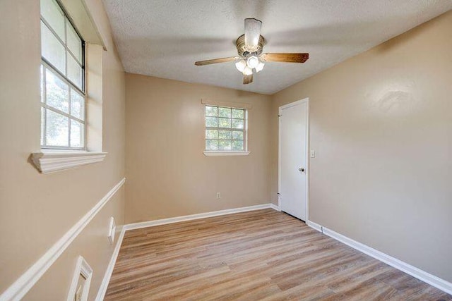 unfurnished room featuring a textured ceiling, light wood-type flooring, visible vents, and a healthy amount of sunlight