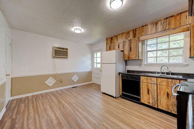 kitchen featuring dishwasher, dark countertops, stove, freestanding refrigerator, and a sink