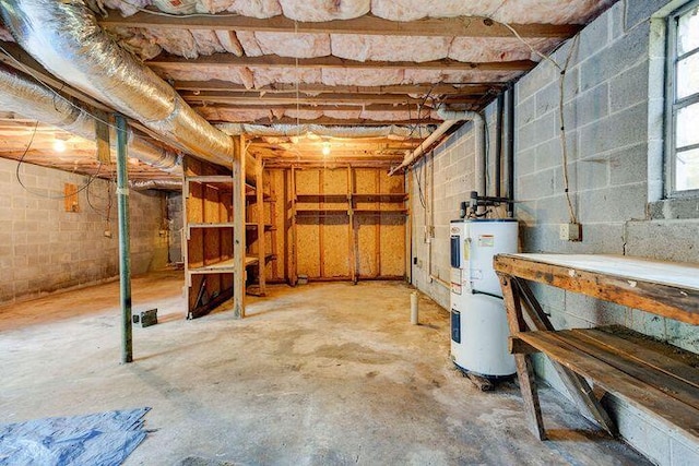 below grade area featuring concrete block wall and electric water heater