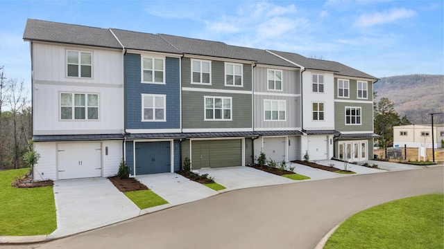 multi unit property with an attached garage, a standing seam roof, a mountain view, and concrete driveway