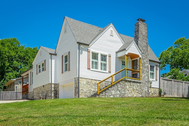 view of front of property with a garage, roof with shingles, fence, and a front lawn