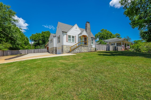 exterior space featuring an attached garage, a chimney, fence, and a lawn