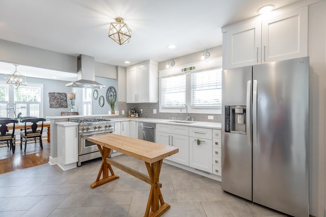 kitchen with stainless steel appliances, light countertops, island exhaust hood, and decorative light fixtures