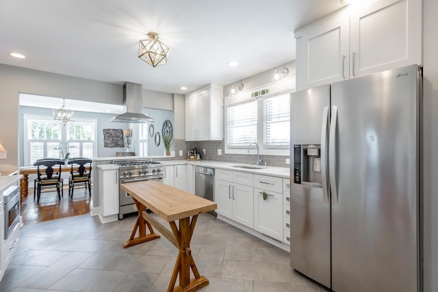 kitchen with decorative light fixtures, island exhaust hood, stainless steel appliances, light countertops, and white cabinets