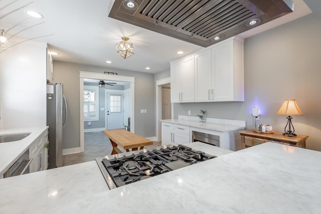 kitchen with appliances with stainless steel finishes, light stone counters, premium range hood, white cabinetry, and recessed lighting